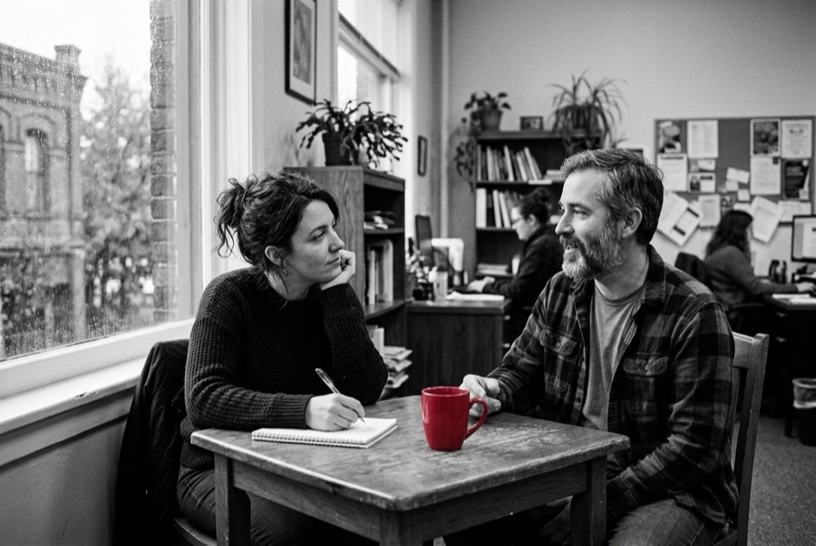 Two people talking through options over coffee at a table by the window