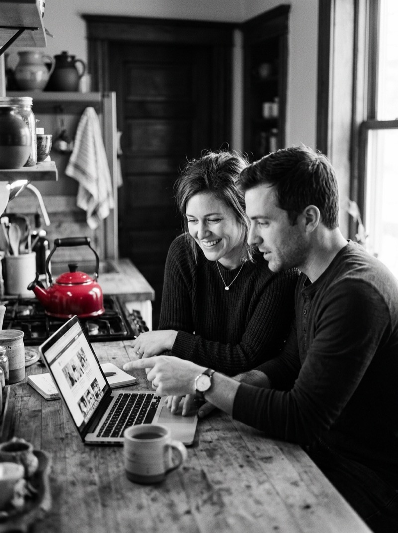 A couple going over their finances together on a laptop at the kitchen table