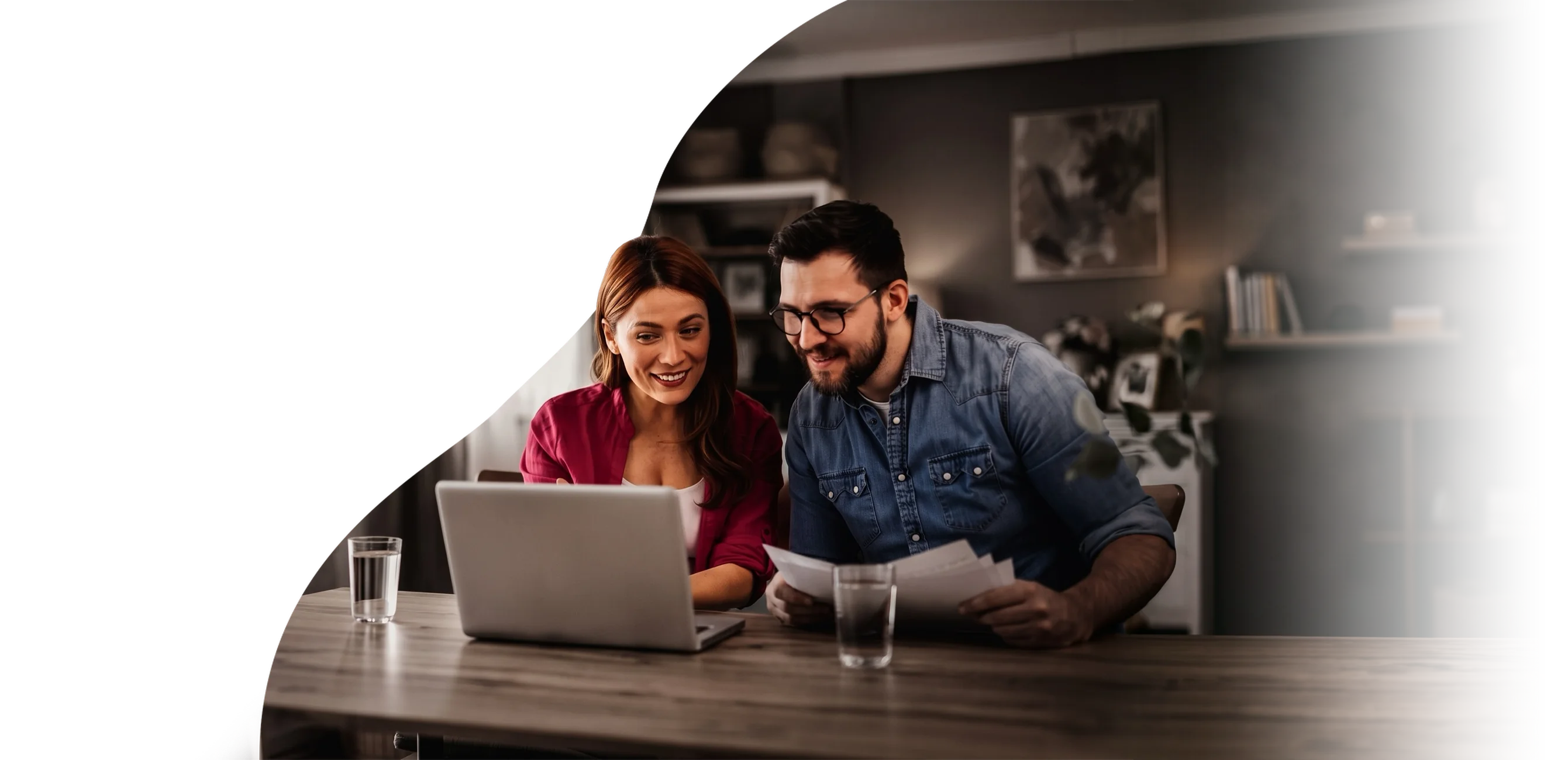 Un couple qui examine ses finances ensemble sur un ordinateur portable à la table de cuisine