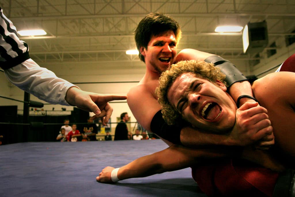 Two men in a wrestling mat on the ground wrestling