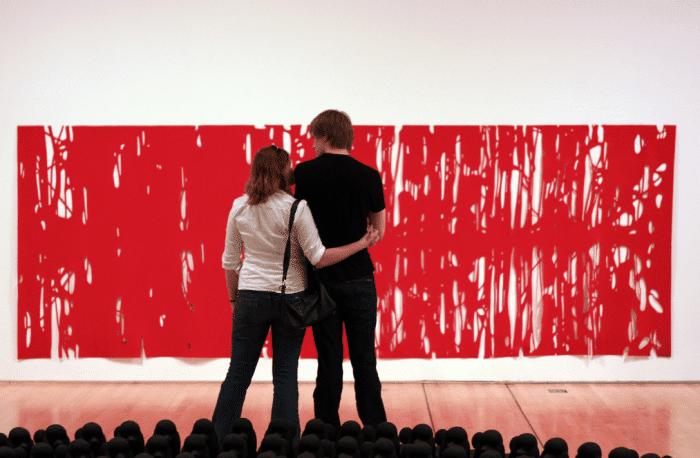 Two people standing in front of a large red painting at a museum