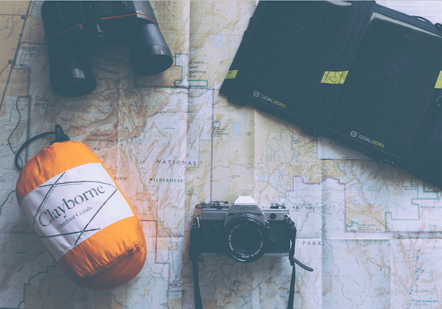 a picture of binoculars, camera, sleeping bag, and map.