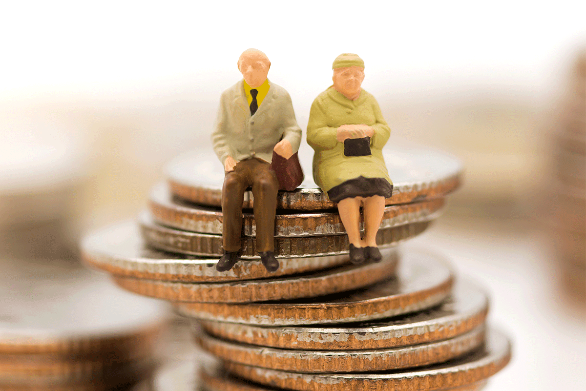 Toy figures of an old couple sitting on stacked coins