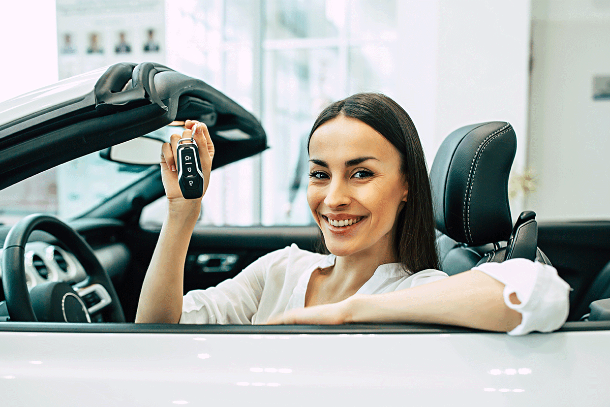 Smiling young women sitting on the driver sit holding the car key