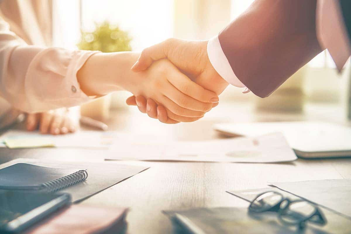 Man and woman are shaking hands in office.