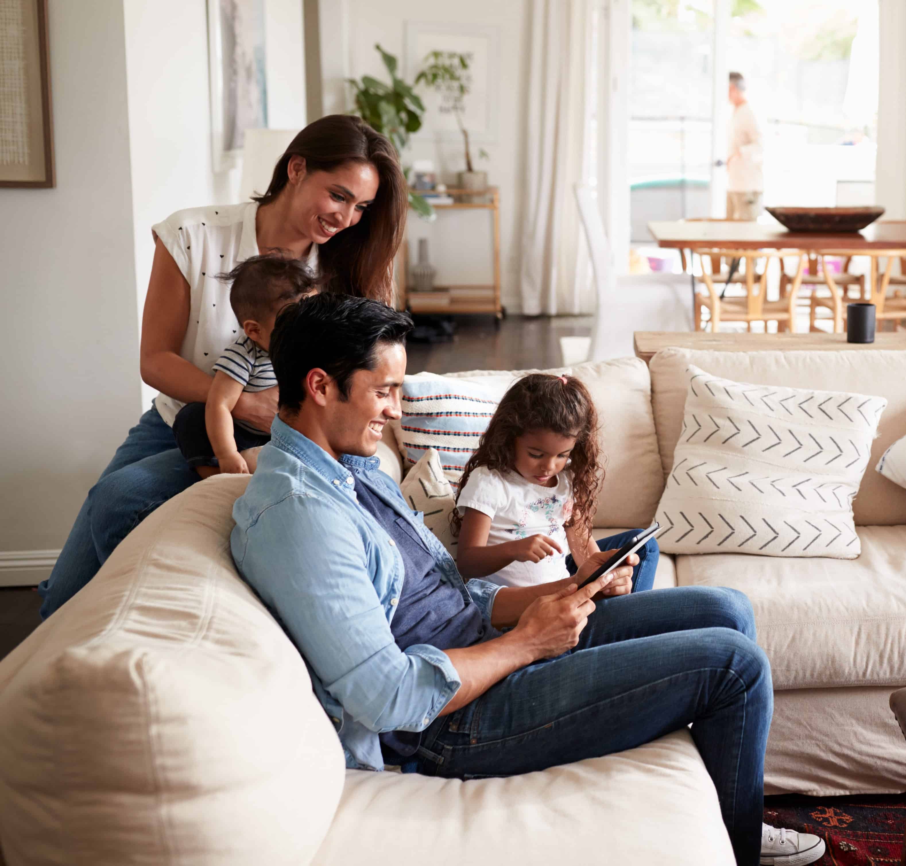 Young family sitting on sofa reading a book together in their living room